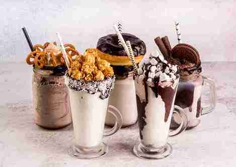 “Delicious gourmet milkshakes topped with donuts, pretzels, popcorn, chocolate, and cookies in glass jars — creamy dessert milkshakes perfect for sweet lovers.”