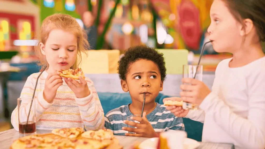 Happy children enjoying a kid-friendly meal and refreshing drinks at a family fast food restaurant.