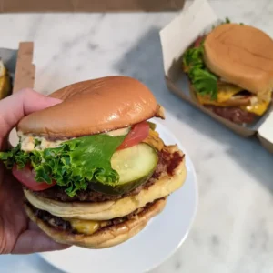 is-shake-shack-worth-it Close-up of Shake Shack ShackBurger showing smashed beef patty, melted cheese, and potato bun