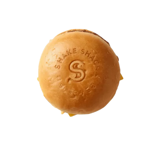 Shake Shack branded potato bun top view with embossed logo and melted cheese visible - signature toasted burger bun close-up