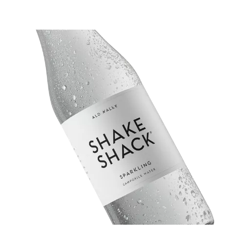 A sleek, chilled glass bottle of Shake Shack Sparkling Water covered in fresh water droplets, featuring a clean white label."