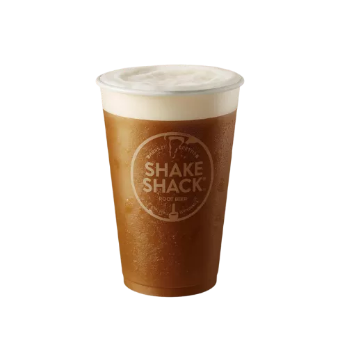 A hand-poured Shake Shack root beer in a plastic cup with a thick, creamy white foam head, illustrating a freshly served craft soda.