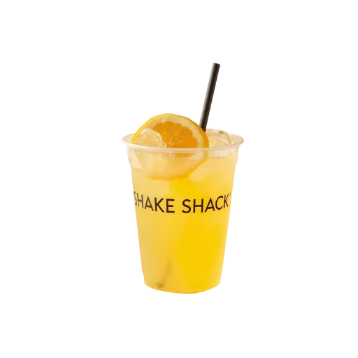 A chilled Shake Shack signature house-made lemonade with ice cubes and a fresh lemon wedge garnish in a transparent branded cup with a black straw